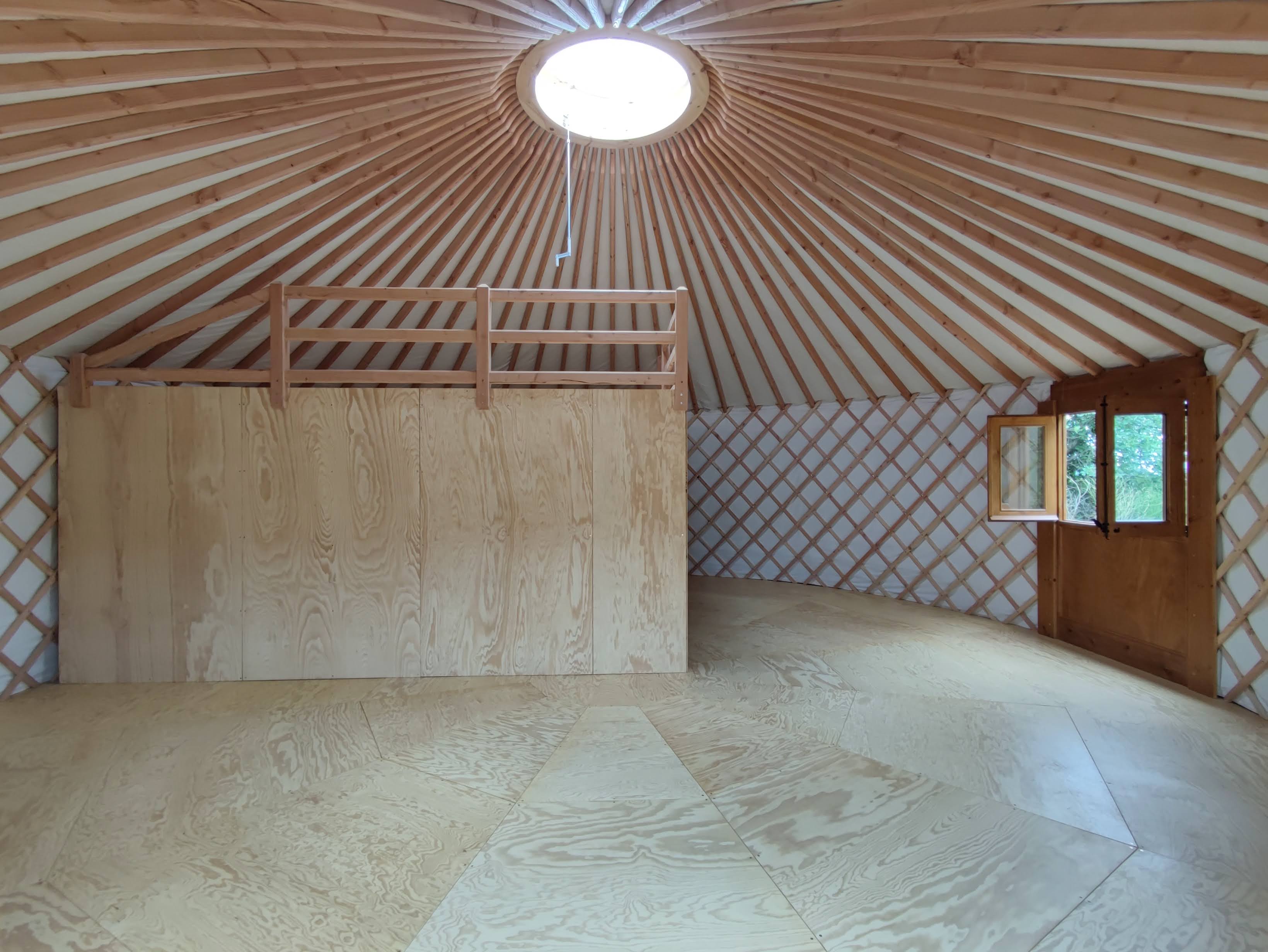 Interior de yurta moderna con altillo habitable y corona visible