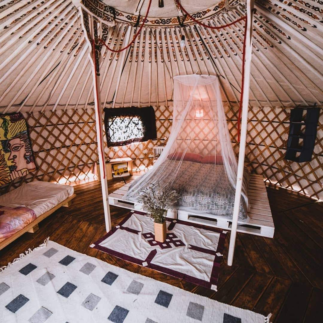 Interior de yurta glamping con cama dosel y decoración cálida